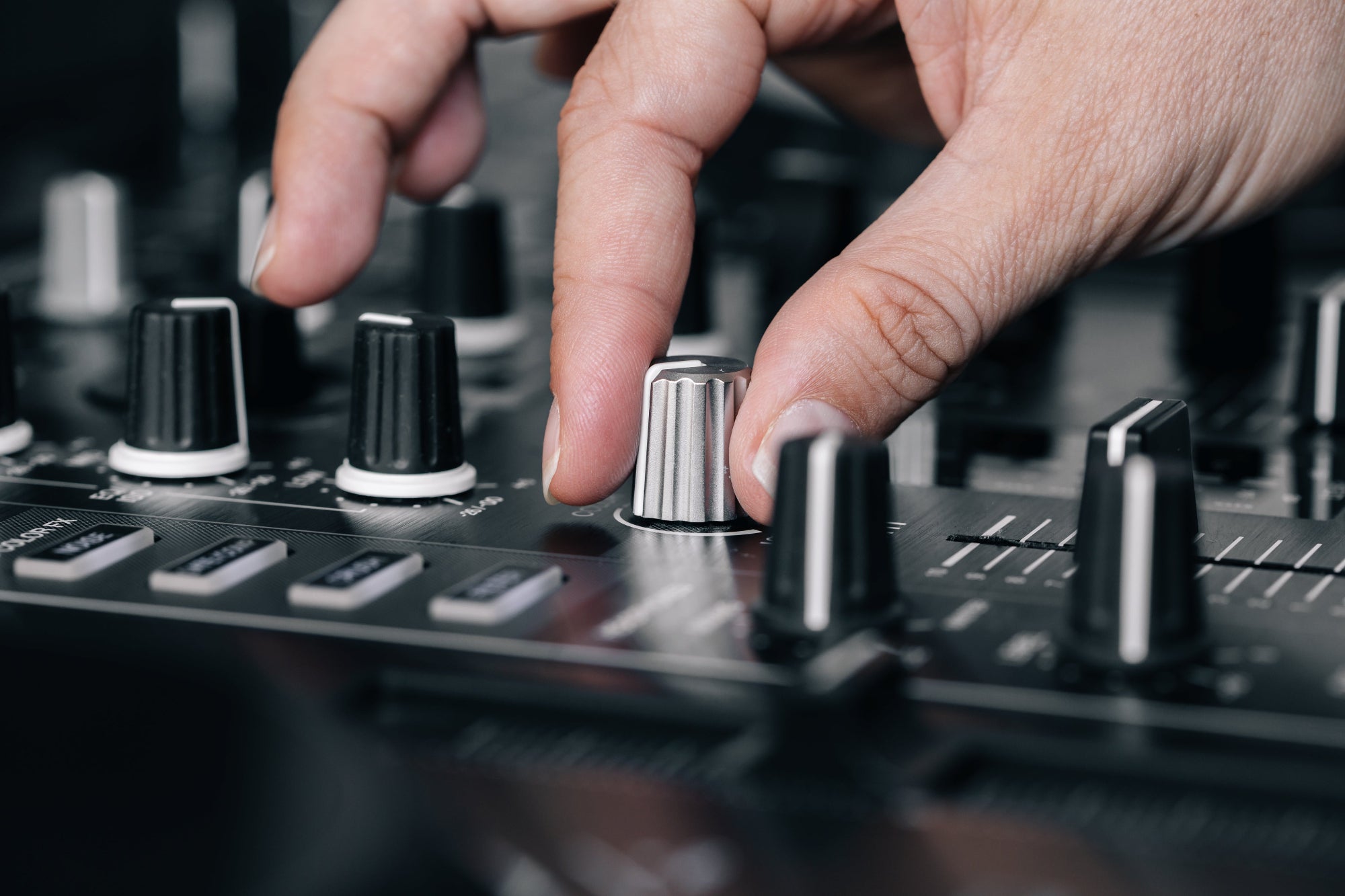 Hand adjusting a knob on a DJ mixer